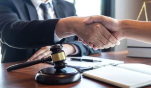 two men shaking hands over a desk with a gavel on it