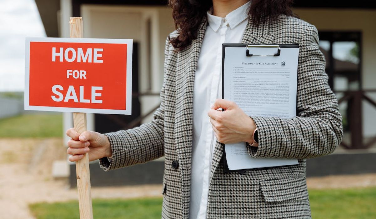 woman holding a house for sale signage