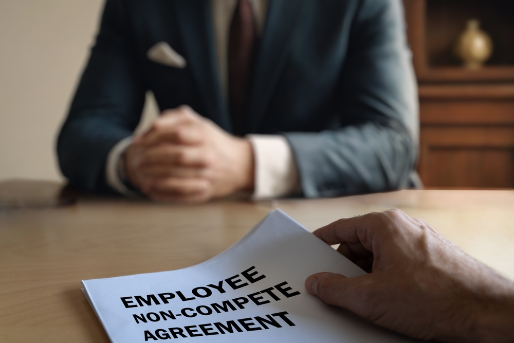 employee handing over a non-compete agreement to an executive in a corporate setting