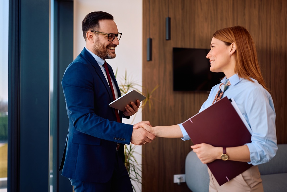 Happy business colleagues handshaking in the office. Focus is on businessman.