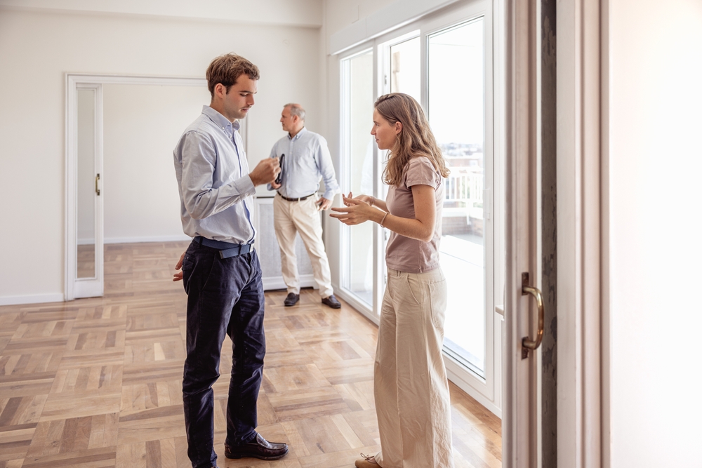 Young couple disagreeing with real estate agent during house viewing